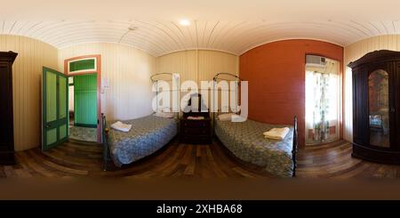 Vue panoramique à 360° de Vue intérieure d'une chambre à l'étage supérieur de l'Imperial Hotel. La chambre est meublée avec un lit jumeaux et un petit bureau ou une table. Les murs sont PA