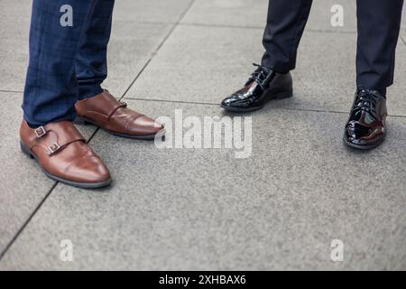 Vue rapprochée de deux paires de chaussures d'homme d'affaires dans un quartier financier animé, symbolisant les affaires et la finance dans l'environnement urbain Banque D'Images