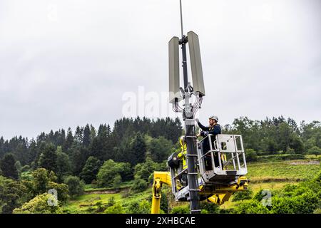 PRODUCTION - 10 juillet 2024, Baden-Württemberg, Forbach : les techniciens se tiennent debout sur une plate-forme élévatrice et travaillent sur un mât de téléphone portable. Dans le cadre d’un projet pilote de couverture de téléphonie mobile en milieu rural, Vodafone coopère avec la société américaine Starlink, dont les satellites peuvent actuellement fournir un accès Internet rapide dans toute l’Europe, l’Amérique du Nord, l’Amérique du Sud et l’Australie. À cet effet, l'opérateur mobile a installé un mât de transmission à Forbach, qui établit le contact avec les serveurs de Vodafone à Francfort via Starlink. Photo : Philipp von Ditfurth/dpa Banque D'Images