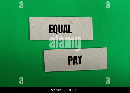 Message d'égalité salariale écrit sur des morceaux de papier avec fond vert. Symbole conceptuel de l'égalité salariale. Copier l'espace. Banque D'Images