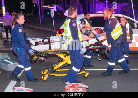 Sydney, Australie. 13 juillet 2024. Une collision dévastatrice s'est produite entre un motocycliste et un jeune livreur de scooter à l'intersection animée de Birrell Street et Carrington Road à Waverley dans la banlieue est de Sydney. La région est connue pour son grand nombre de livreurs de nourriture sur scooters et vélos. Photo : un cavalier grièvement blessé pris en charge par des ambulanciers paramédicaux. Crédit : Robert Wallace / Wallace Media Network / Alamy Live News Banque D'Images