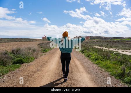 Femme avec les bras ouverts sur la route avec le dos à la caméra. Débuts de nouvelles voies et de nouveaux objectifs Banque D'Images