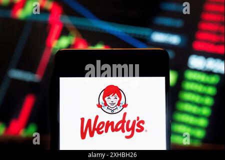 Chine. 21 juin 2024. Dans cette illustration photo, le logo de la chaîne de restauration rapide américaine Wendy's (NASDAQ : WEN) vu sur un smartphone avec un graphique d'indice boursier économique en arrière-plan. (Photo de Budrul Chukrut/SOPA images/SIPA USA) *** strictement à des fins éditoriales *** crédit : SIPA USA/Alamy Live News Banque D'Images