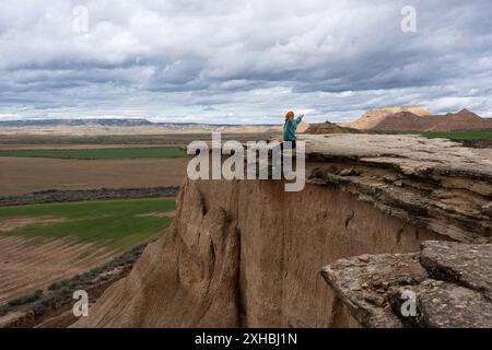 Femme aux bras ouverts assise sur des falaises rocheuses. Femme se sentant libre Banque D'Images