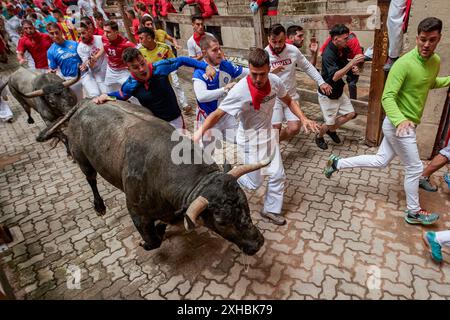 Pampelune, Espagne. 13 juillet 2024. Plusieurs jeunes hommes courent devant des taureaux pendant la course des taureaux pendant les festivités de San Fermín 2024. (Photo par Elsa A Bravo/SOPA images/SIPA USA) crédit : SIPA USA/Alamy Live News Banque D'Images