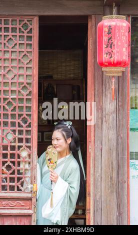 Jeune femme en robe traditionnelle chinoise dans une ouverture de porte à Suzhou, Chine Banque D'Images