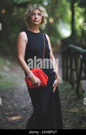 Femme blonde mature élégante sur un chemin forestier Banque D'Images