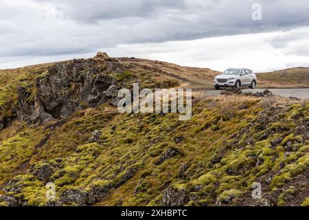 Voiture hors route garée au bord de la falaise volcanique envahie de mousse dans le canyon de Gjain, vallée de Thjorsardalur, sud de l'Islande. Banque D'Images