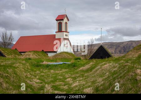 Ferme Keldur en Islande avec l'église Keldnakirkja de 1875 et rangée de vieilles maisons de gazon envahies d'herbe et de mousse. Banque D'Images