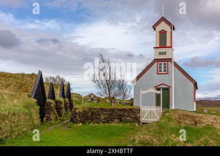 Ferme Keldur en Islande avec l'église Keldnakirkja de 1875 et rangée de vieilles maisons de gazon envahies d'herbe et de mousse. Banque D'Images