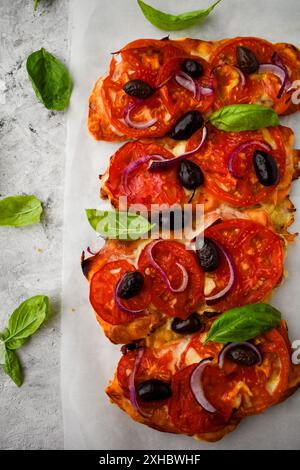 Bruschetta savoureuse à la mozzarella, tomates, olives noires et basilic sur un papier cuisson brun. Set d'encas italiens antipasti. Banque D'Images
