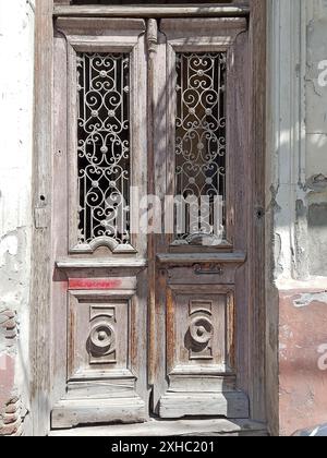 Cette image capture le charme rustique d'une paire de portes en bois vieilli, chacune ornée de ferronneries et de motifs complexes. Les portes servent de test Banque D'Images