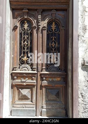 Cette image capture le charme rustique d'une paire de portes en bois vieilli, chacune ornée de ferronneries et de motifs complexes. Les portes servent de test Banque D'Images