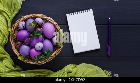 Oeufs de Pâques, violet et lilas, avec un bloc-notes pour l'écriture, maquette, sur une table en bois gris, carte de Pâques, bannière, mise au point sélective, horizontale Banque D'Images