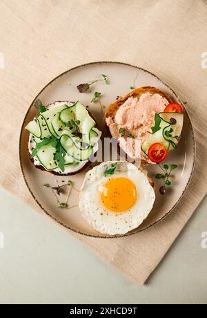 Assortiment de sandwichs, pain blanc, oeuf frit, fromage à la crème et concombre, caviar de capelan, pain au sésame, petit déjeuner, sur une table blanche, pas de monde Banque D'Images