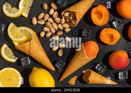 Cônes de crème glacée avec des citrons, des abricots et des pistaches avec des glaçons sur un fond noir Banque D'Images