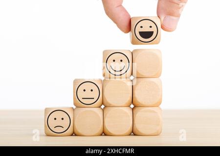 La main choisit le visage souriant sur un bloc de bois. Excellent service d'affaires pour l'expérience client. Concept d'enquête de satisfaction. Copier l'espace Banque D'Images