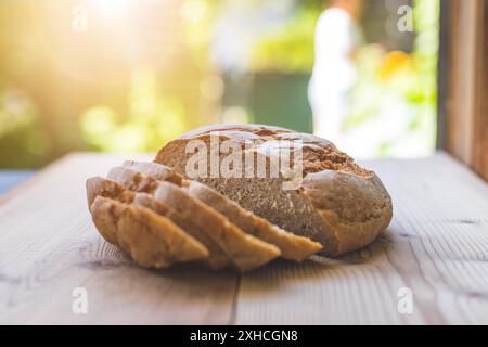 Pain frais foncé en tranches, allongé sur une planche à découper en bois. Arrière-plan flou et flou Banque D'Images