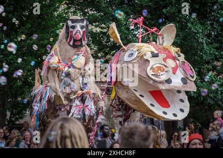 Folkestone, Kent, Royaume-Uni. 13 juillet 2024. Défilé annuel du Charivari Day. Folklore britannique et traditions rituelles sont le thème de la saisissante parade du carnaval de cette année. Des sculptures massives de tête ornent les épaules des jeunes locaux avec des enfants de l'école primaire à travers le district habillant aux couleurs du thème de l'année. Marchant du stade, en passant par la ville jusqu’au kiosque à musique Leas, le Charivari Day reste la plus grande tradition coutumière de Folkestone depuis 1997 et attire des centaines de spectateurs dans la ville portuaire en bord de mer. Crédit : Guy Corbishley/Alamy Live News Banque D'Images