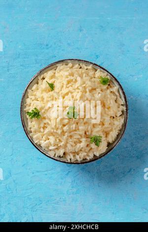 Riz cuit avec des feuilles de persil frais, grenaille au-dessus sur fond bleu avec un endroit pour le texte Banque D'Images