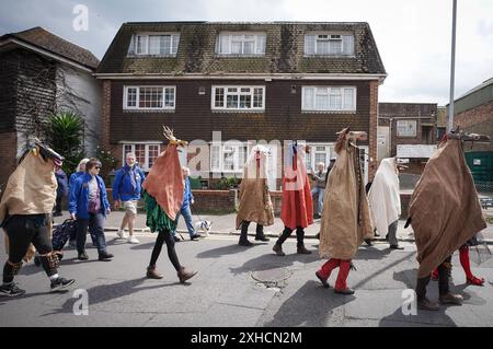 Folkestone, Kent, Royaume-Uni. 13 juillet 2024. Défilé annuel du Charivari Day. Folklore britannique et traditions rituelles sont le thème de la saisissante parade du carnaval de cette année. Des sculptures massives de tête ornent les épaules des jeunes locaux avec des enfants de l'école primaire à travers le district habillant aux couleurs du thème de l'année. Marchant du stade, en passant par la ville jusqu’au kiosque à musique Leas, le Charivari Day reste la plus grande tradition coutumière de Folkestone depuis 1997 et attire des centaines de spectateurs dans la ville portuaire en bord de mer. Crédit : Guy Corbishley/Alamy Live News Banque D'Images