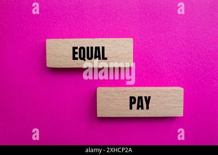 Message d'égalité de salaire écrit sur des blocs de bois avec fond rose. Symbole conceptuel de l'égalité salariale. Copier l'espace. Banque D'Images