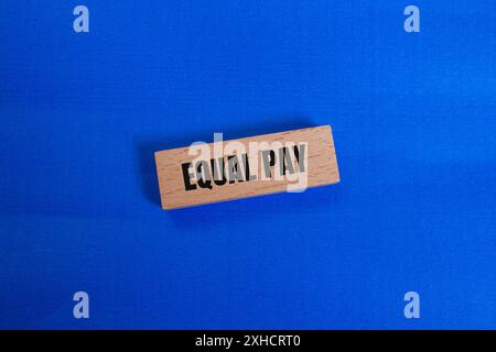 Message de salaire égal écrit sur bloc de bois avec fond bleu. Symbole conceptuel de l'égalité salariale. Copier l'espace. Banque D'Images