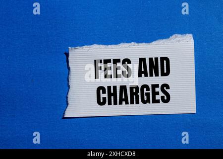 Frais et charges mots écrits sur papier blanc déchiré avec fond bleu. Symbole des frais et frais conceptuels. Copier l'espace. Banque D'Images