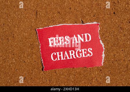 Frais et charges mots écrits sur un morceau de papier rouge déchiré avec fond brun. Symbole des frais et frais conceptuels. Copier l'espace. Banque D'Images
