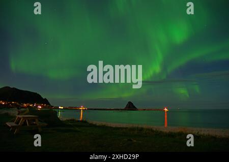 Aurores boréales vertes dans un ciel nocturne clair sur une mer et une plage, avec des montagnes en arrière-plan, Bleik, Vesteralen, Langoya, Nordland, Norvège Banque D'Images