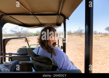 Femme touriste sur un safari en Afrique, voyageant dans une voiture avec un toit ouvert regarder les animaux Banque D'Images