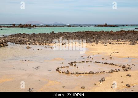 Plage dans le nord de l'île avec de l'eau peu profonde et un sable blanc, avec des roches volcaniques. Contour d'un coeur, fait de pierres. Caleton Blanco Banque D'Images