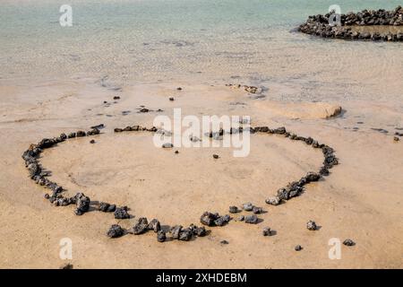 Plage dans le nord de l'île avec de l'eau peu profonde et un sable blanc, avec des roches volcaniques. Contour d'un coeur, fait de pierres. Caleton Blanco Banque D'Images