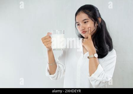 Jeune femme asiatique n'aime pas ou évite de boire un verre de lait indigestion problèmes de santé de l'estomac. fond blanc isolé Banque D'Images