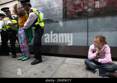 Londres, Angleterre, Royaume-Uni. 13 juillet 2024. Un manifestant est assis sur le trottoir menotté après avoir été arrêté pour ne pas être sorti de la route tandis qu'un autre manifestant est fouillé par des policiers à Marble Arch pendant la manifestation. La demande des jeunes est déterminée à perturber les premières semaines de Keir Starmer au gouvernement. Ils sont déterminés à faire clairement comprendre que le nouveau gouvernement travailliste ne les représente pas et qu'ils ne soutiennent pas la complicité du parti travailliste dans le génocide à Gaza. (Crédit image : © Martin Pope/ZUMA Press Wire) USAGE ÉDITORIAL SEULEMENT! Non destiné à UN USAGE commercial ! Banque D'Images