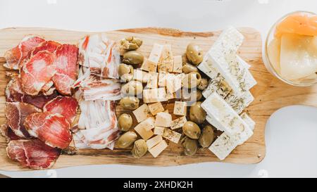Plateau d'apéritif avec prosciutto, bacon, fromage, olives et feta sur planche en bois Banque D'Images