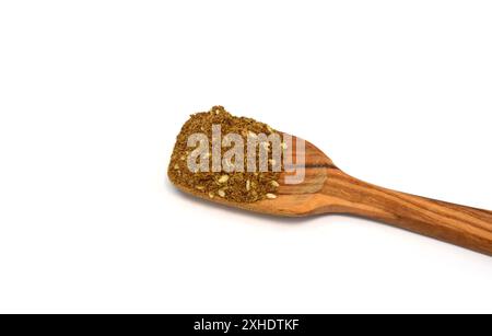 Épice Zaatar dans une cuillère en bois isolée sur blanc. Pile de zatar (za'atar), un mélange d'épices du moyen-Orient avec des graines de sésame, du sel, de l'origan, du thym.. Banque D'Images