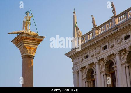 Vue rapprochée d'un sommet d'une colonne de Saint Théodore (saint patron de Venise) et de la façade de la Bibliothèque de marque. Place Saint Marc. Venise, Italie. Banque D'Images