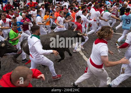 Pampelune, Navarre, Espagne. 13 juillet 2024. Plusieurs coureurs devant le groupe de taureaux de combat du ranch José Escolar Gil courent le long de la rue Estafeta en direction des arènes de Pampelune. Septième jour de la course traditionnelle des taureaux pendant les festivités de San FermÃ-n. A cette occasion, les courageux taureaux du ranch José Escolar Gil ont fait leurs débuts dans les rues de la vieille ville de la capitale navarrese. (Crédit image : © Nacho Boullosa/SOPA images via ZUMA Press Wire) USAGE ÉDITORIAL SEULEMENT! Non destiné à UN USAGE commercial ! Banque D'Images