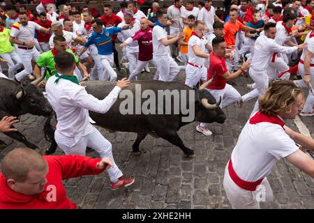 Pampelune, Navarre, Espagne. 13 juillet 2024. Plusieurs coureurs devant le groupe de taureaux de combat du ranch José Escolar Gil courent le long de la rue Estafeta en direction des arènes de Pampelune. Septième jour de la course traditionnelle des taureaux pendant les festivités de San FermÃ-n. A cette occasion, les courageux taureaux du ranch José Escolar Gil ont fait leurs débuts dans les rues de la vieille ville de la capitale navarrese. (Crédit image : © Nacho Boullosa/SOPA images via ZUMA Press Wire) USAGE ÉDITORIAL SEULEMENT! Non destiné à UN USAGE commercial ! Banque D'Images