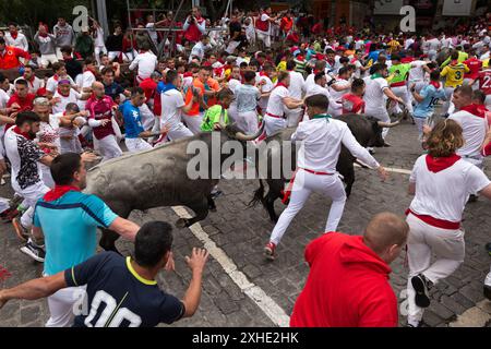 Pampelune, Navarre, Espagne. 13 juillet 2024. Plusieurs coureurs devant le groupe de taureaux de combat du ranch José Escolar Gil courent le long de la rue Estafeta en direction des arènes de Pampelune. Septième jour de la course traditionnelle des taureaux pendant les festivités de San FermÃ-n. A cette occasion, les courageux taureaux du ranch José Escolar Gil ont fait leurs débuts dans les rues de la vieille ville de la capitale navarrese. (Crédit image : © Nacho Boullosa/SOPA images via ZUMA Press Wire) USAGE ÉDITORIAL SEULEMENT! Non destiné à UN USAGE commercial ! Banque D'Images