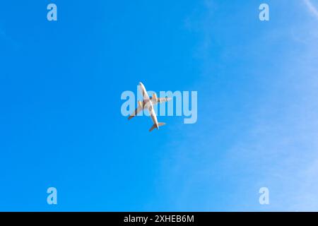 Avion volant à travers le ciel bleu clair. L'avion blanc vole dans le ciel au-dessus d'un ciel bleu. Le ciel est clair et le soleil brille Banque D'Images