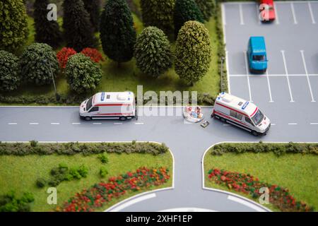 Modèle d'ambulances sur route à côté de paramédics miniatures avec patient sur civière. Voitures jouets et arbres. Concept pour les services médicaux d'urgence - Mosco Banque D'Images