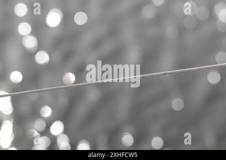 Une corde en acier inoxydable, résistante aux acides avec un tissage sur un fond abstrait avec bokeh. Banque D'Images