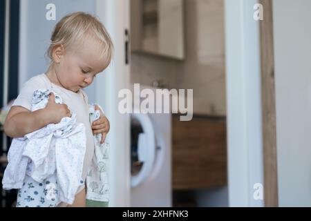 petite fille d'enfant caucasien aide la mère avec une lessive Banque D'Images