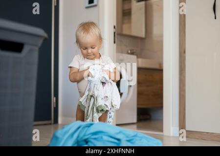 petite fille d'enfant caucasien aide la mère avec une lessive Banque D'Images