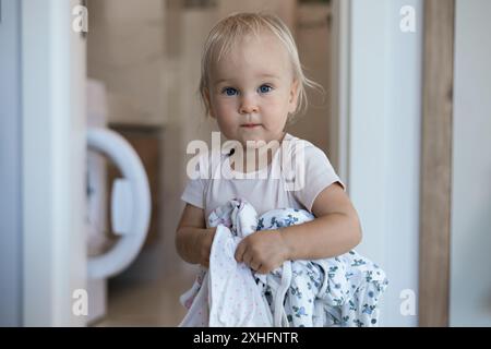 petite fille d'enfant caucasien aide la mère avec une lessive Banque D'Images