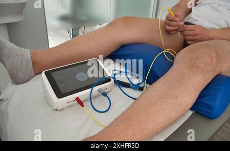 Photo d'une machine de neuro-modulation entre les jambes d'un patient Banque D'Images