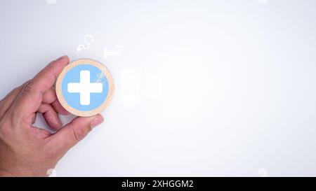 Main humaine tenant un signe plus et icône médicale de santé sur fond blanc, concept d'assurance maladie, santé et accès au concept de santé sociale, Banque D'Images