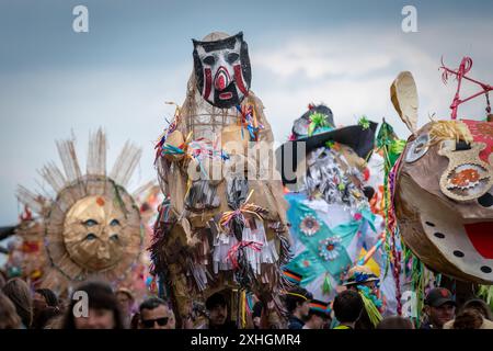 Folkestone, Kent, Royaume-Uni. 13 juillet 2024. Défilé annuel du Charivari Day. Folklore britannique et traditions rituelles sont le thème de la saisissante parade du carnaval de cette année. Des sculptures massives de tête ornent les épaules des jeunes locaux avec des enfants de l'école primaire à travers le district habillant aux couleurs du thème de l'année. Marchant du stade, en passant par la ville jusqu’au kiosque à musique Leas, le Charivari Day reste la plus grande tradition coutumière de Folkestone depuis 1997 et attire des centaines de spectateurs dans la ville portuaire en bord de mer. Crédit : Guy Corbishley/Alamy Live News Banque D'Images